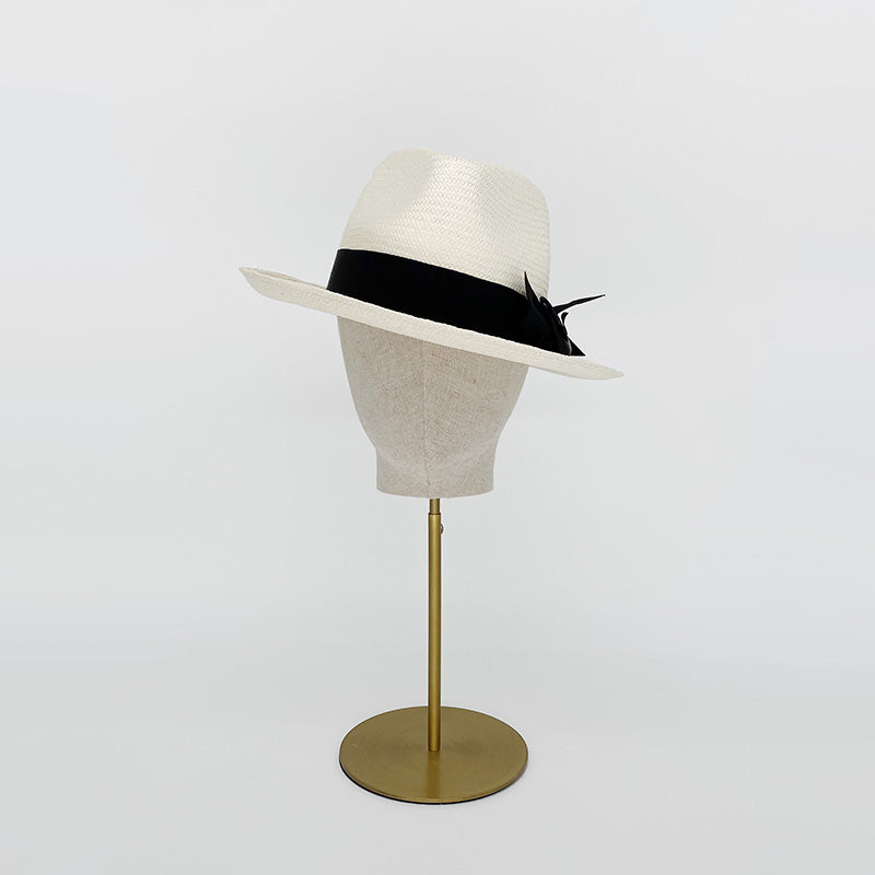 Photo of a white panama trilby with a grosgrain bow on a linen display head