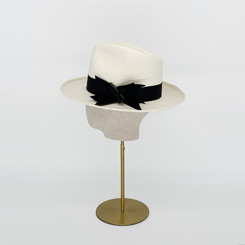 Side view of a white panama trilby with a grosgrain bow on a linen display head
