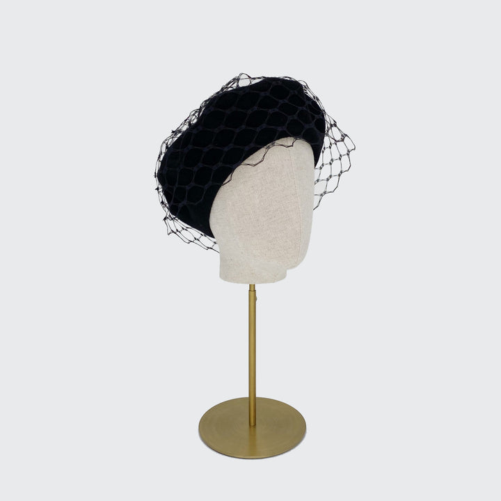Photo of a black wool beret with black veiling on a linen display head