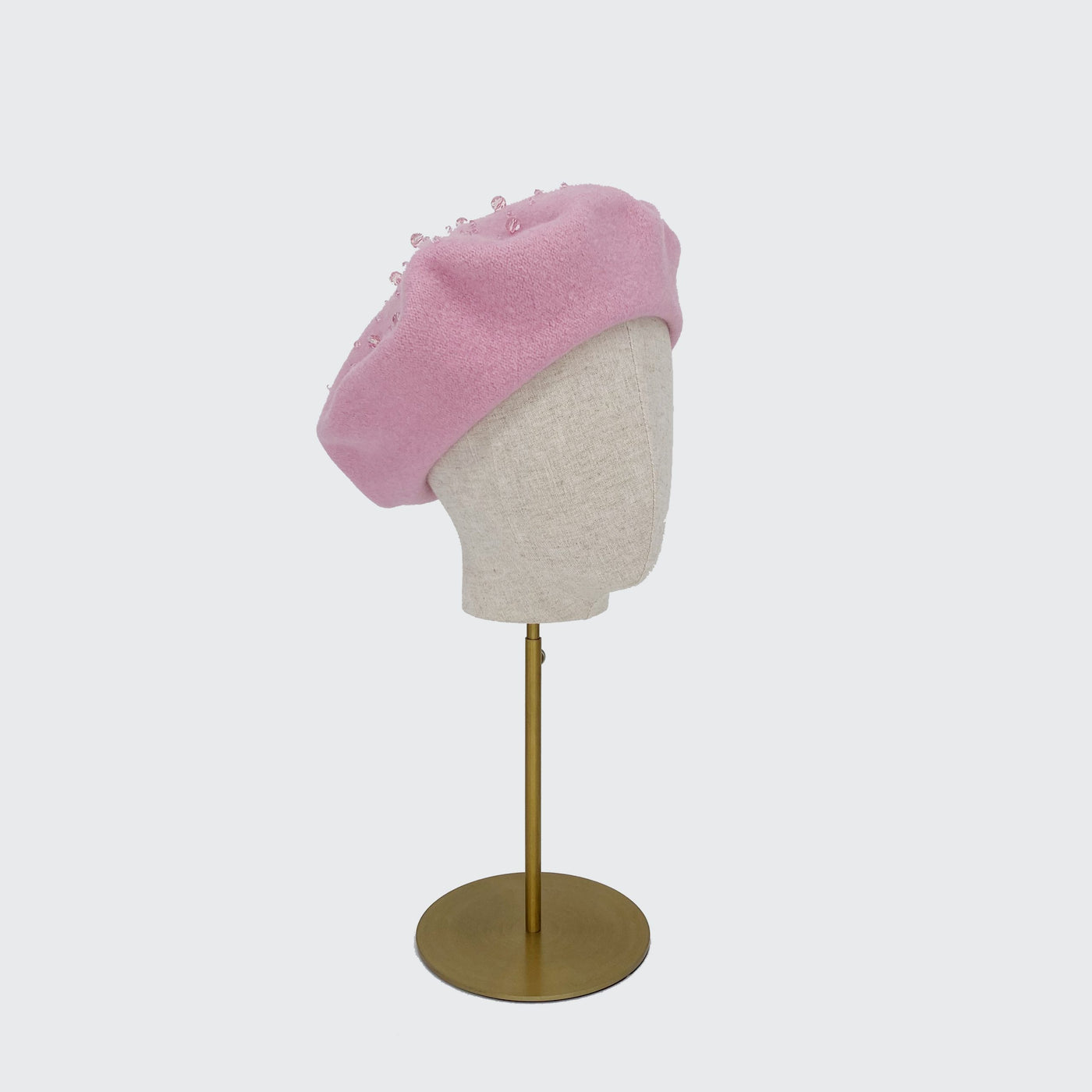 Photo of a pale pink wool beret with crystals on a linen display head