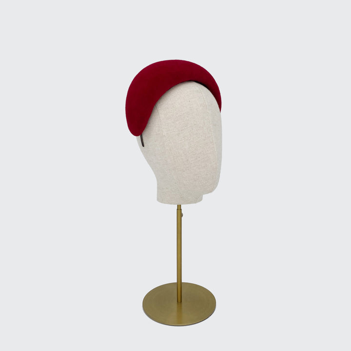 Side view of a red velour felt wide headband on a linen display head