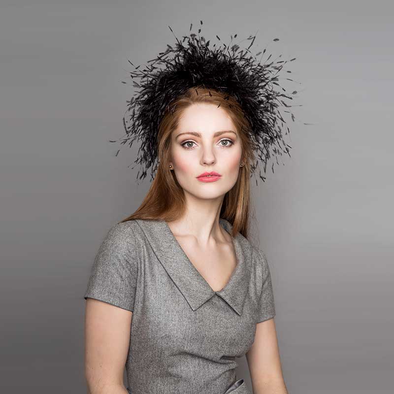Woman with long hair wearing a grey dress and a black ostrich feather Jackie O pillbox