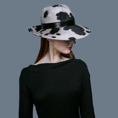 Woman with red hair wearing a black dress and a cow pattern velour felt fedora with a black patent band
