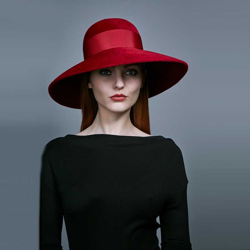 Woman with red hair wearing a black dress and a red velour felt downbrim with a grosgrain band