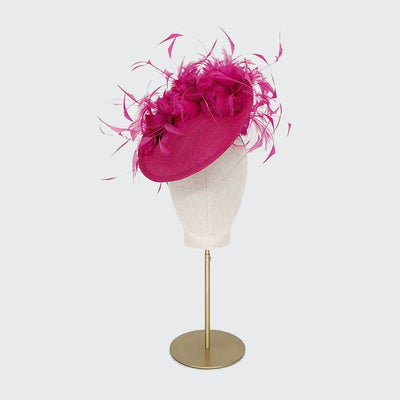 Photo of a pink straw disc with feather flowers on a linen display head