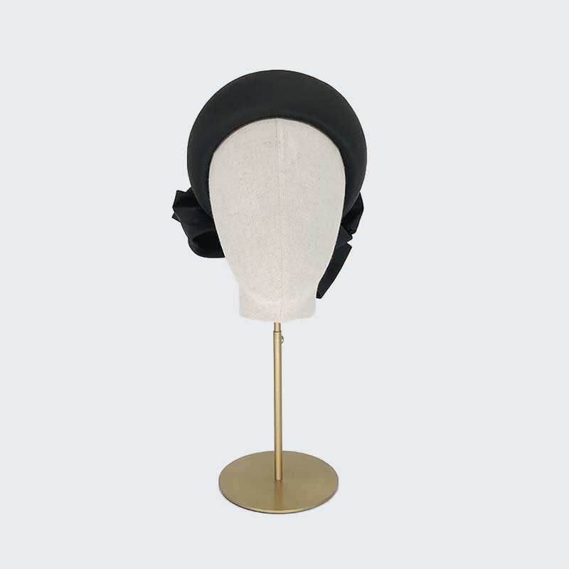 Photo of a black taffeta silk Jackie O pillbox with bows on a linen display head