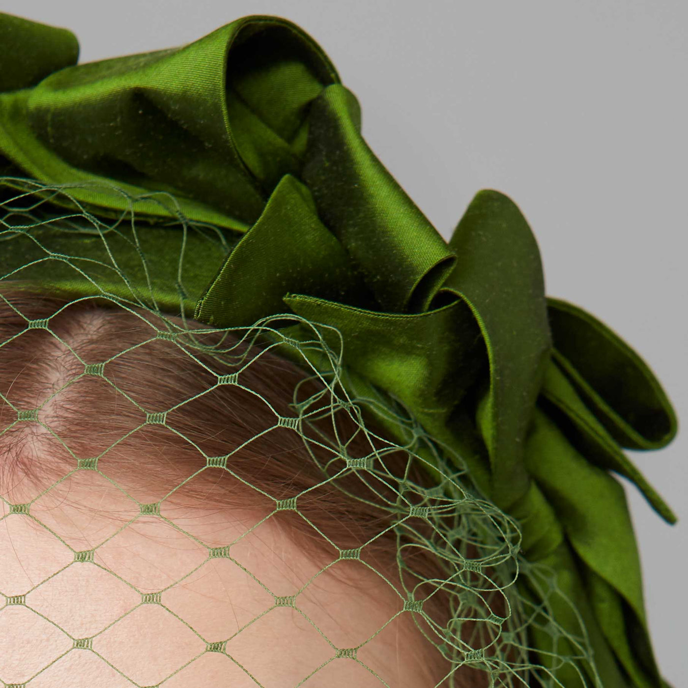 Close up of a green silk bow headband with face veil 