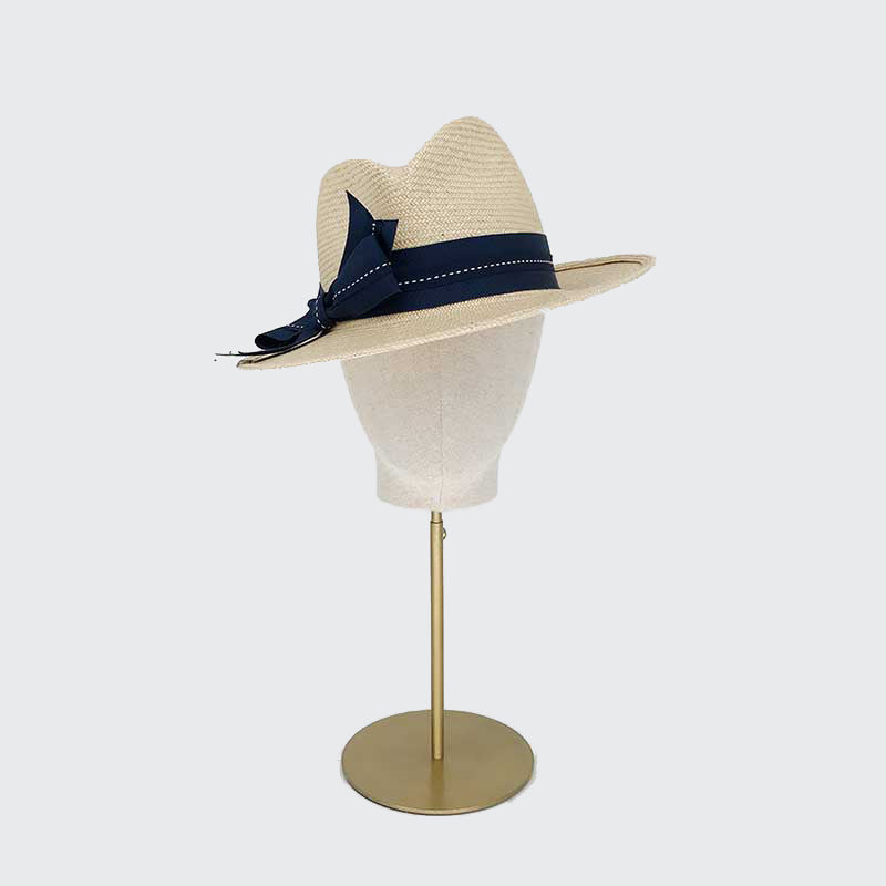 Photo of a natural panama trilby with a navy grogsrain band with an ivory running through it on a linen display head
