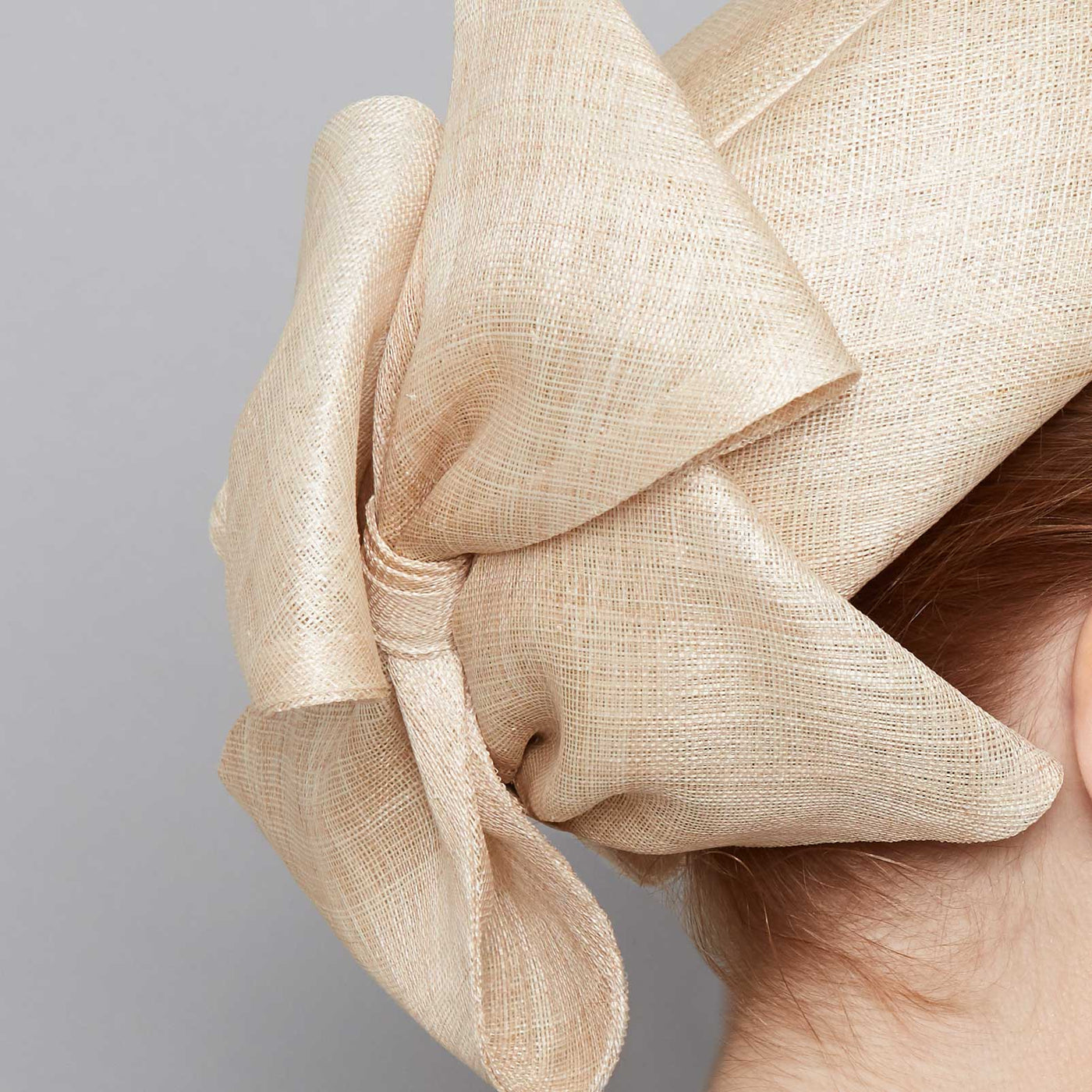 Close up of a natural fine straw Jackie O pillbox with bows on a linen display head