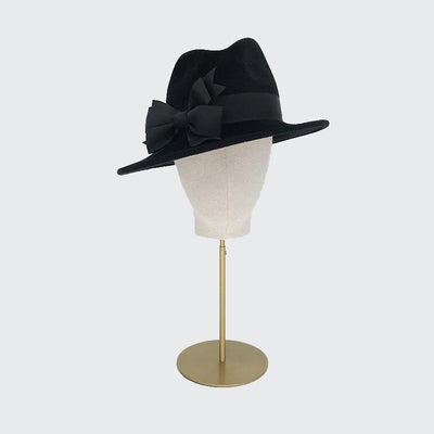 Photo of a black velour felt tall crown trilby with double bows on a linen display head