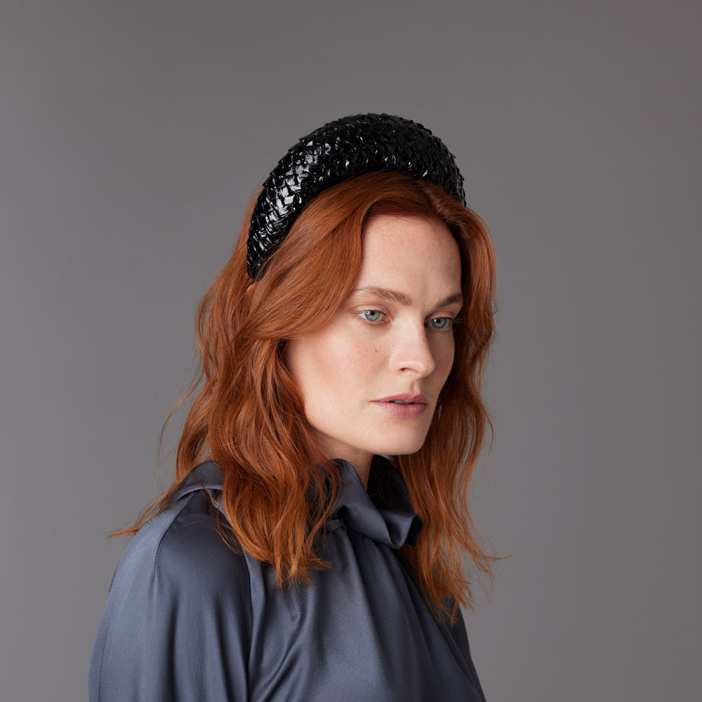 Woman with red hair wearing a grey top and a black patent straw raised headband