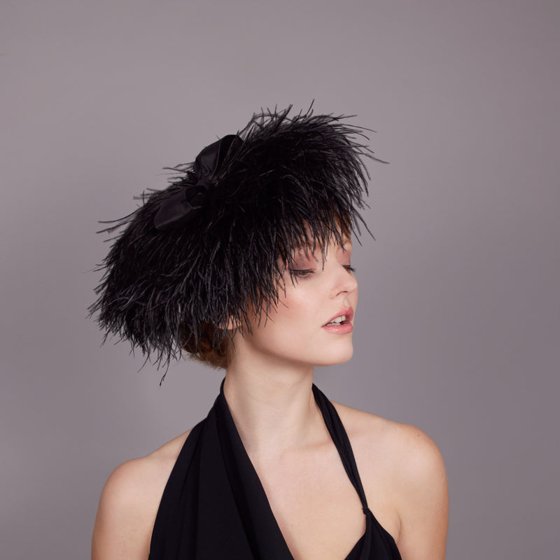 Woman wearing a black dress and a black ostrich feather disc