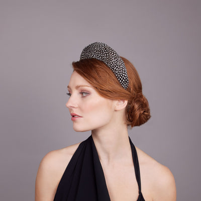 Woman with red hair wearing a black dress and a guinea fowl feather covered headband
