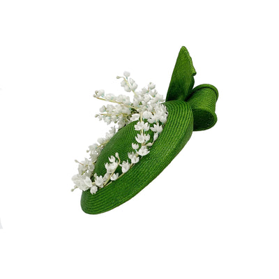 Photo of a green straw button pillbox with lily of the valley and a bow