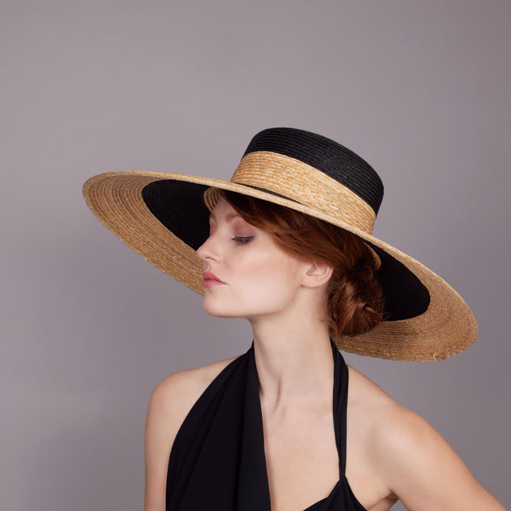 Woman with red hair wearing a black dress and a two-tone Italian straw summer hat