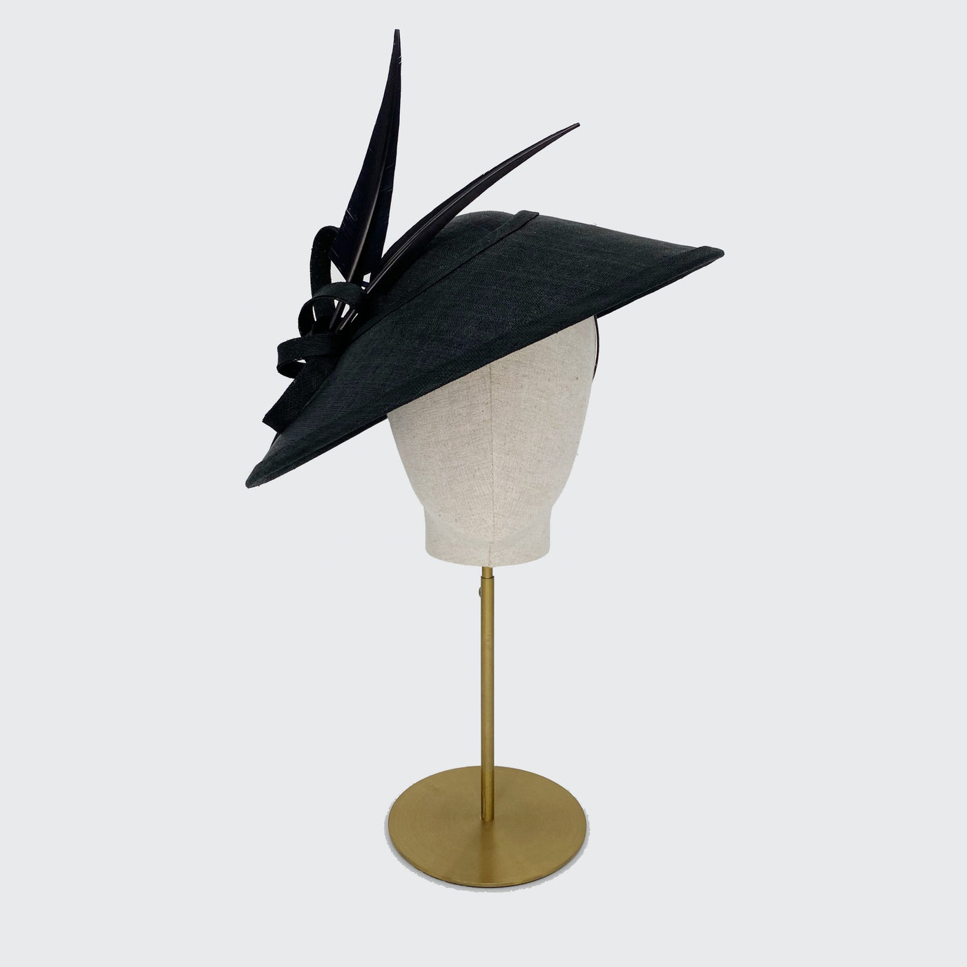 Photo of a black fine straw Charlene with black sharp feathers on a linen display head