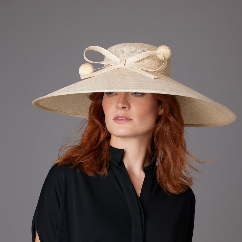 Woman with red hair wearing a black shirt and a natural fine straw downbrim with a natural bow and two hat pins