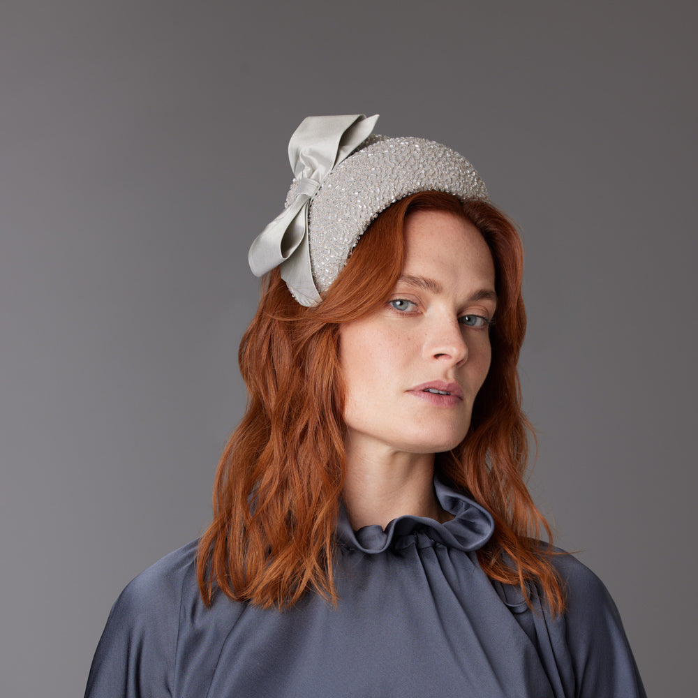 Woman with red hair wearing a grey top and a silver grey beaded silk crescent with a bow