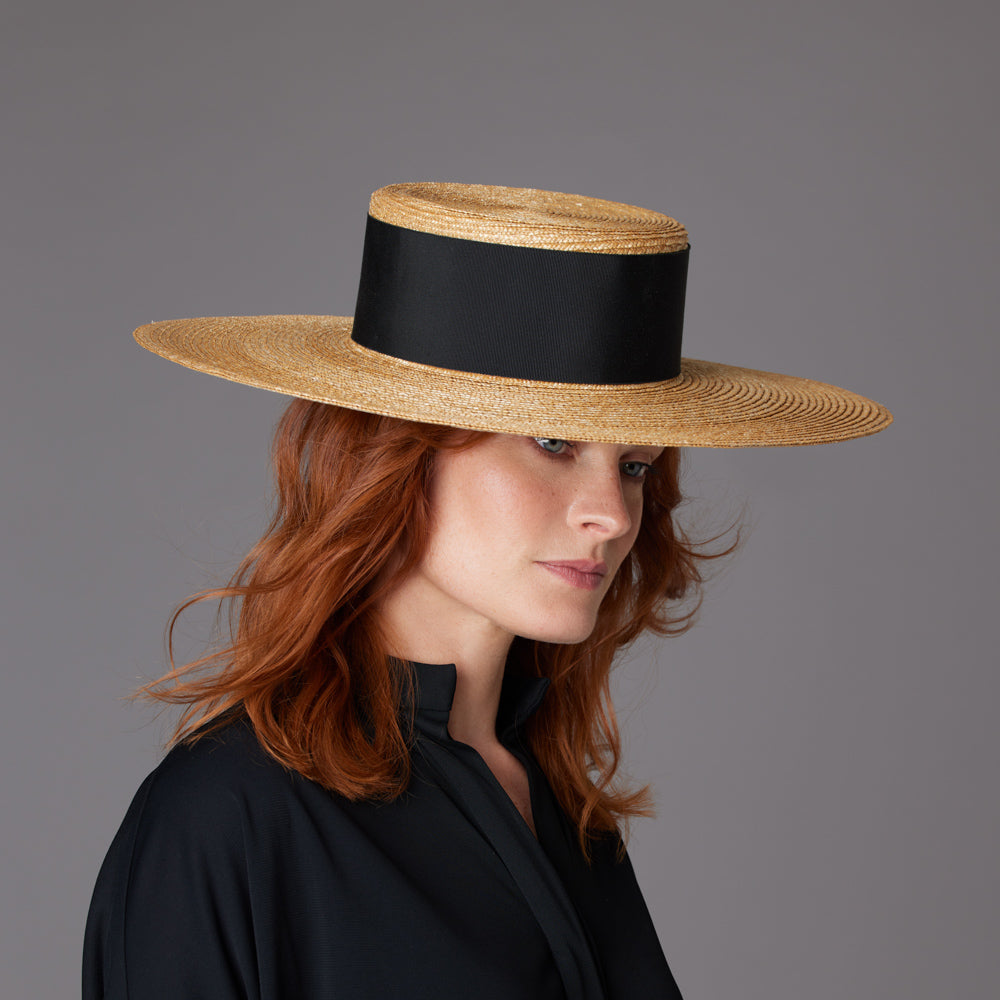 Woman with red hair wearing a black blouse and a natural Italian straw boater with a wide band