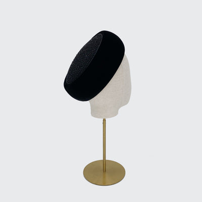 Photo of a black velvet Jackie O pillbox with a silk beaded top on a linen display head