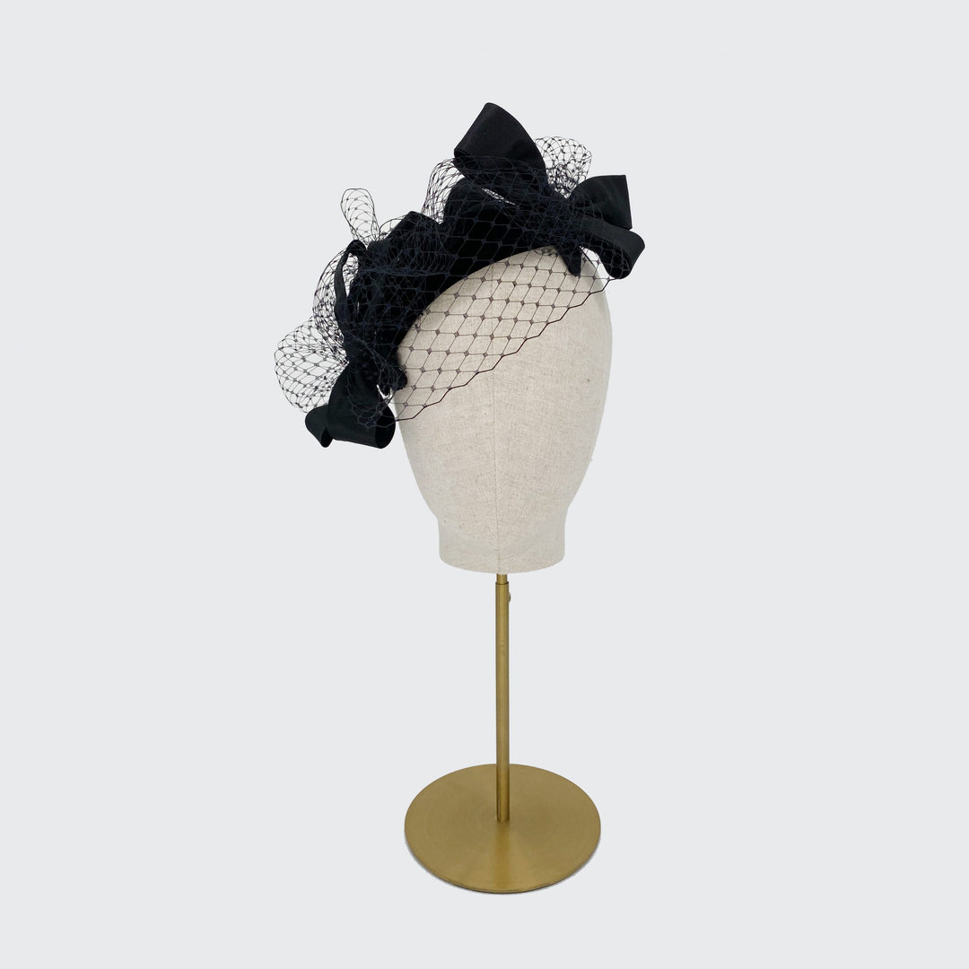 Black silk trio of bows headpiece with veiling on a linen display head