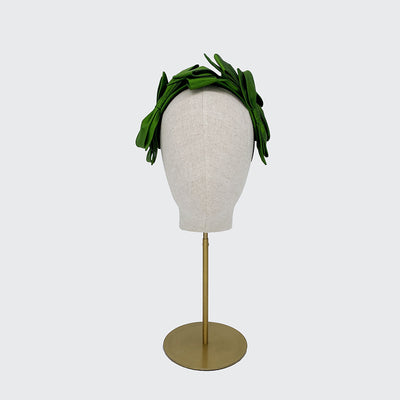 Photo of a green silk bow headband on a linen display head