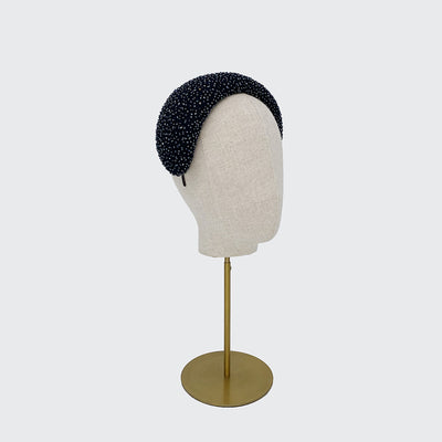 Side view of a navy silk beaded wide crescent headband on a linen display head