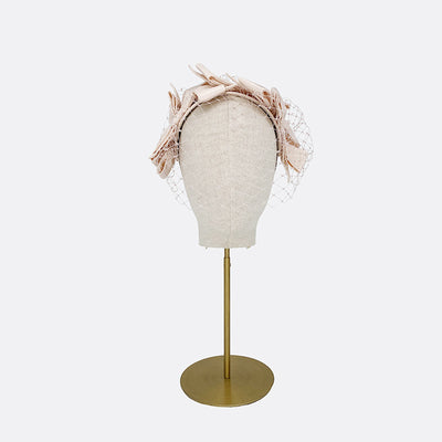 Photo of a pale pink silk bow headband with face veil on a linen display head