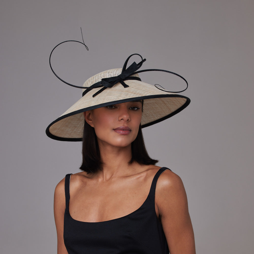 Woman with dark hair wearing a black dress and a natural downbrim with a black thin bow and black quills