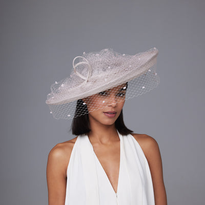 Woman with dark hair wearing a white dress and a nude pink ridge sidesweep with spotty veiling