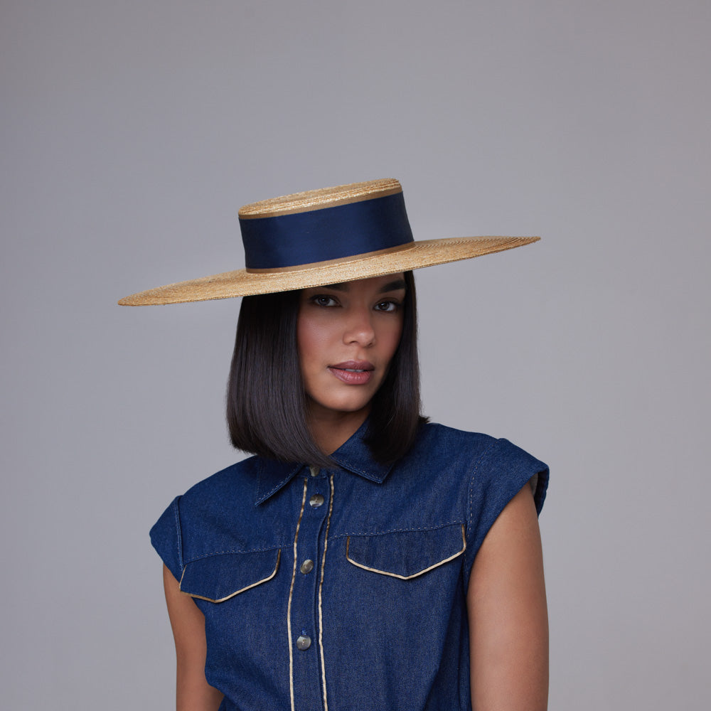 Woman with dark hair wearing a denim dress and a natural Italian straw boater with a navy grosgrain band